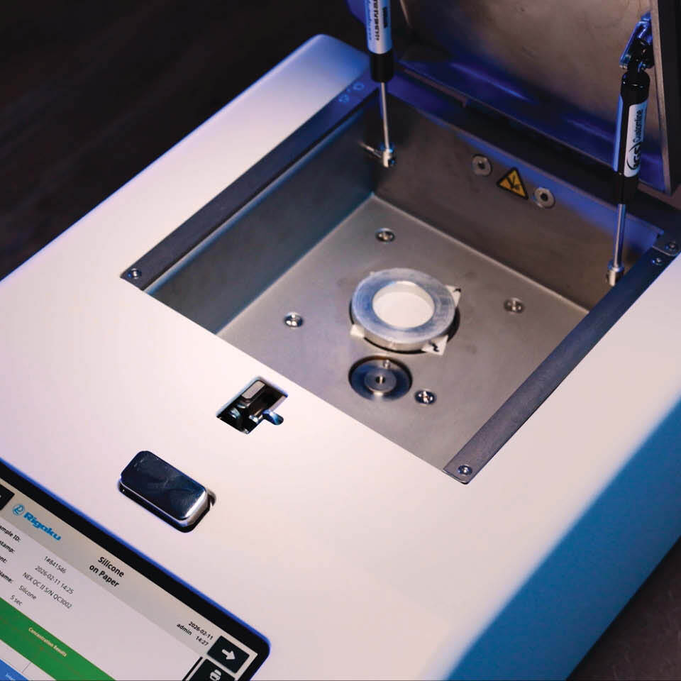 NEX QC II, an elemental analyzer, displayed with an open sample chamber containing a silicone coated paper sample coupon, ready for testing.