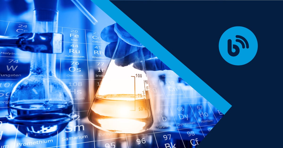 flasks with liquid in front of periodic table